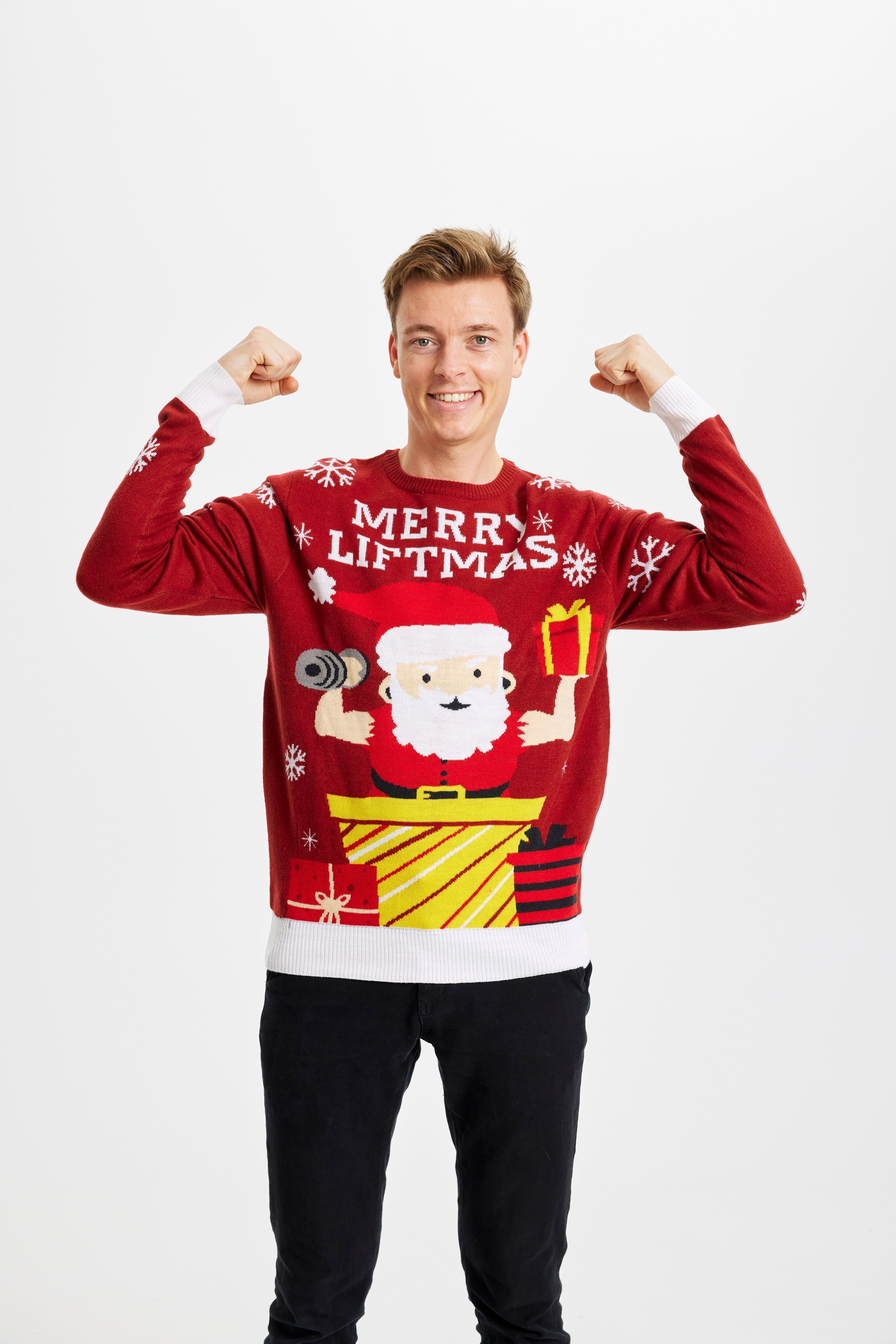 Un homme posant portant un pull rouge de Noël avec la citation